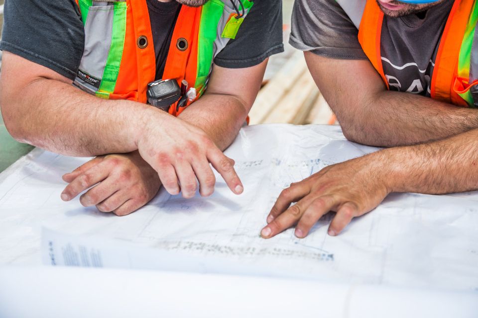 Two workers reviewing project plans together on site