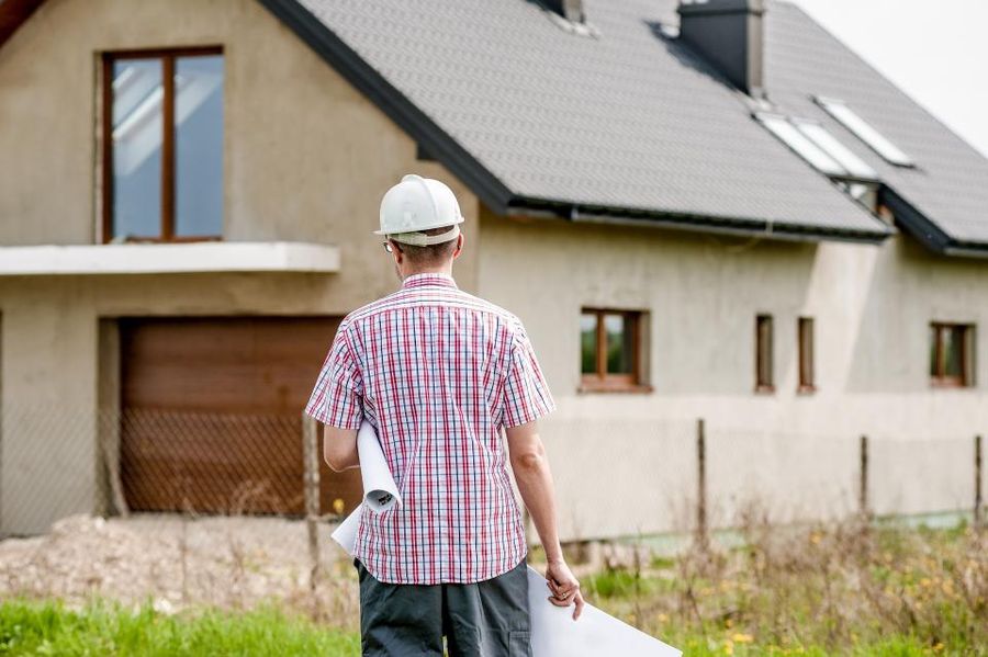Project manager with plans in front of a house under construction